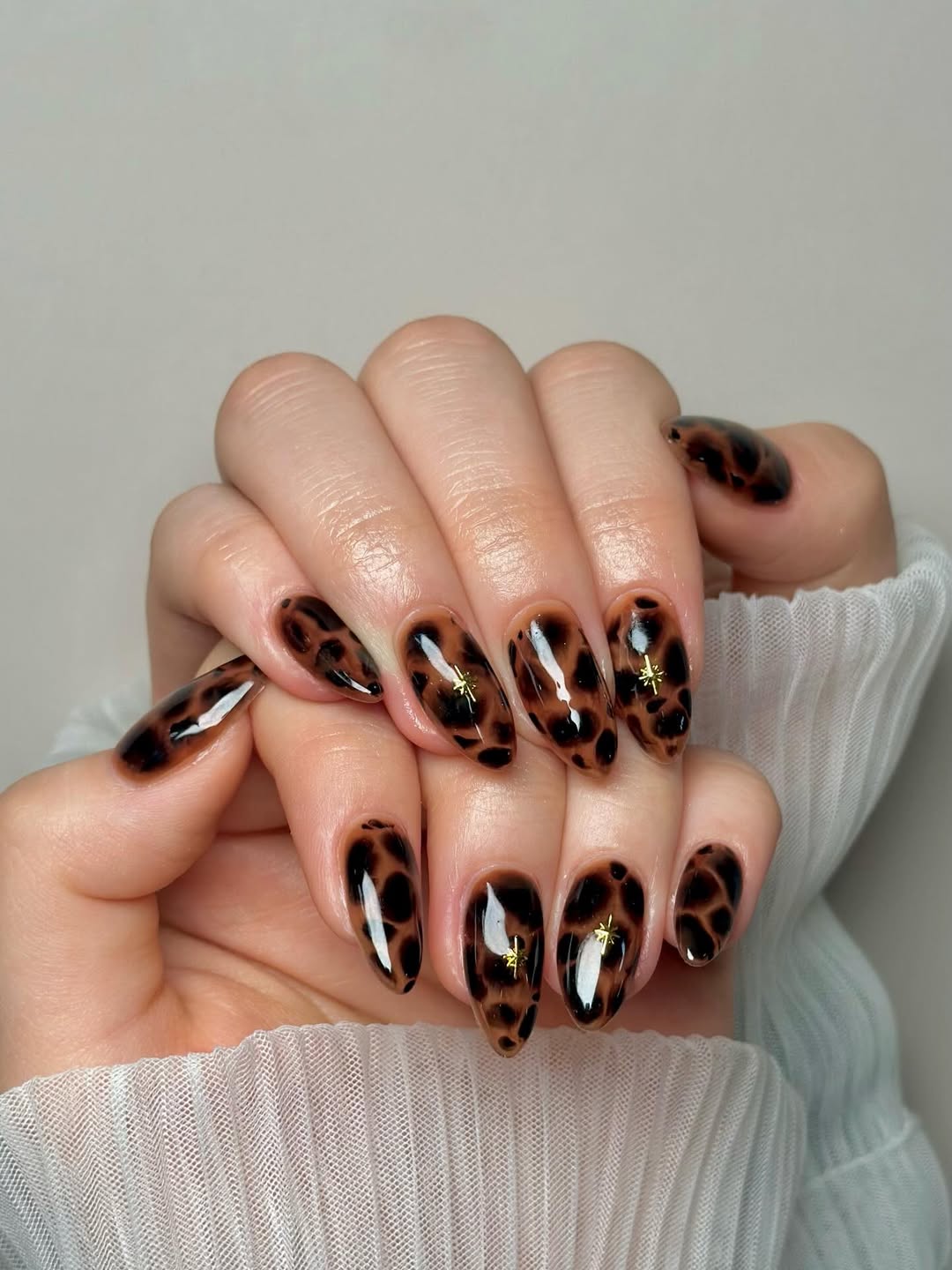 Glossy Tortoiseshell Almond Nails With Gold Stars